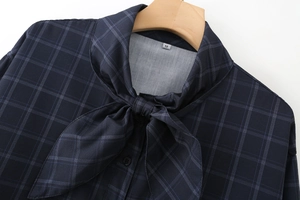 Dettaglio camicia a quadretti blu navy con elegante fiocco al collo ed etichetta M