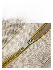 Macro detail of electroplated polished metal zipper on a coarse linen lunch handbag