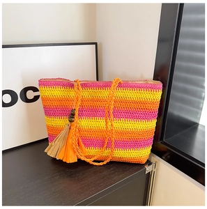 Detail of colorful rainbow woven straw tote bag featuring decorative wooden bead tassels