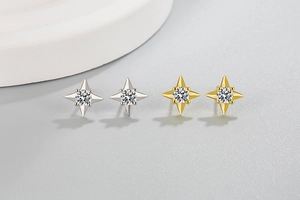 Dettaglio di orecchini a lobo a stella a quattro punte in oro e argento con cristalli