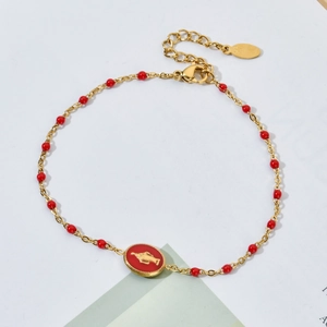 Detail of gold chain bracelet with red beads and oval red enamel religious pendant