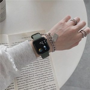 Close-up of a digital watch with green silicone strap paired with silver chain jewelry