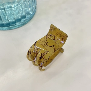 Détail de la pince à cheveux en résine ambrée marbrée avec design à 6 dents