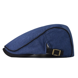 Detail of blue cotton beret hat showing knit texture and bronze metal side buckle