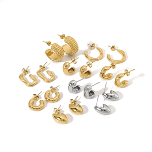 Collection of geometric C-shaped and twisted gold and silver hoop earrings on white background