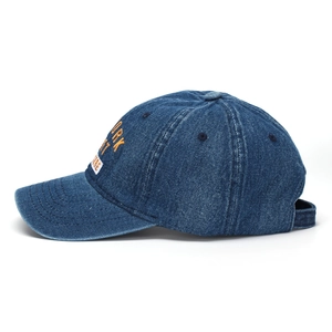 Detail of yellow and white New York embroidery on navy blue washed denim baseball cap