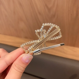 Close-up of golden metal bow hair clip with pearl inlays and elegant craftsmanship