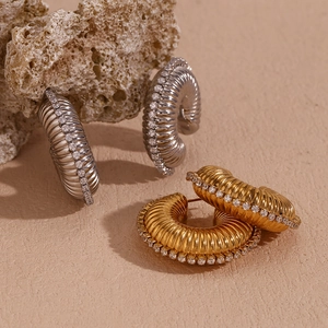 Macro detail of gold and silver textured hoop earrings with sparkling zircon inlay