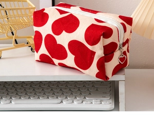 Detail of canvas makeup bag with red hearts and heart-shaped metal zipper pull