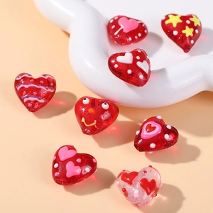 Macro shot of red heart-shaped glass beads with polka dots and wave patterns for DIY