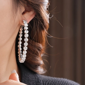 Close-up of a large silver hoop earring with sparkling rhinestones on a female model