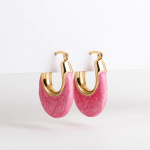 Detailed macro view of U-shaped golden earrings with pink marbled enamel inlay detail