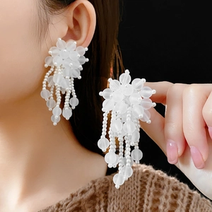Dettaglio di orecchini a nappa con perle bianche indossati per un look sofisticato