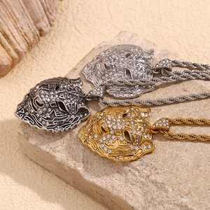 Three hip hop tiger head pendants in gold, silver, and black on a rustic stone background