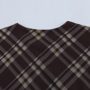 Vue macro détaillée du tissu à carreaux marron foncé et du col rond de cette robe vintage