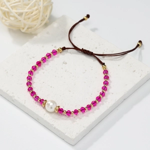 Macro detail of a rose red crystal bead bracelet with a large white pearl and gold accents