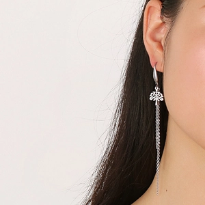 Macro shot of silver metallic snake pattern chain earrings with intricate relief texture