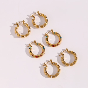 Detail of three gold hoop earrings with pearls and colorful cubic zirconia inlay