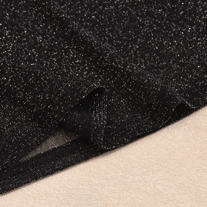 Détail du tissu noir pailleté avec ourlet en maille fine sur le haut à manches longues