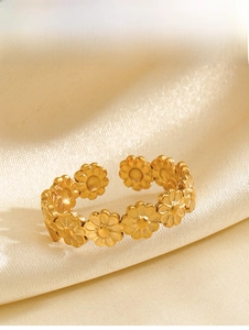 Detailed close-up of a golden daisy chain open ring on elegant silk fabric