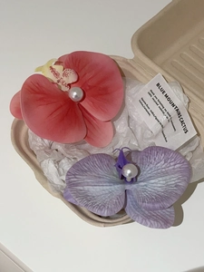 Detail of pink and purple orchid flower clips with pearls in a minimalist gift box