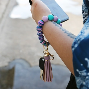 Silicone beaded wristlet keychain with purple tassel and marbled beads on woman arm
