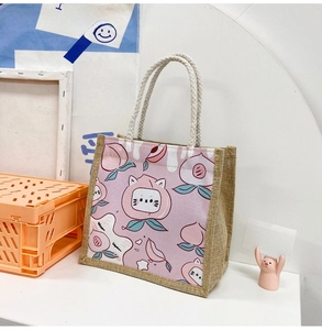 Detail of jute tote bag showing cartoon peach cat print and twisted hemp rope handles