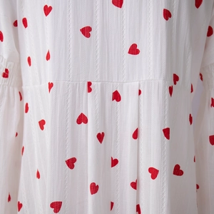 Détails d'imprimés cœurs rouges sur tissu coton texturé blanc avec taille plissée fine