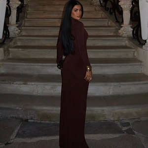 Détail d'une élégante robe longue en maille marron foncé avec col montant et fente latérale