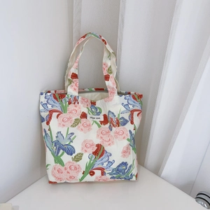 Détail du sac cabas en toile fleurie avec roses roses, iris bleus et étiquette simple