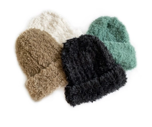 Flat lay of plush knit beanies in black, khaki, beige, and mint green colors