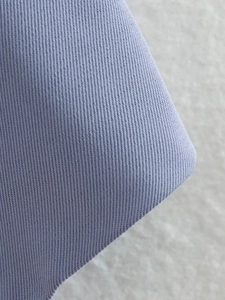 Gros plan macro montrant la texture fine du tissage sergé du tissu gilet lilas