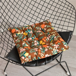 Nahaufnahme braunes Sitzkissen mit Blumenmuster auf einem schwarzen Metallgitterstuhl