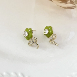 Detailed macro view of green enamel flower earrings with sparkling zircon center
