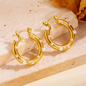 Nahaufnahme von 18K vergoldeten Creolen mit Hammerschlag-Optik und Perlen auf Stein