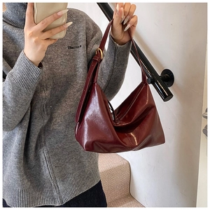 Detail of burgundy glossy leather tote bag with gold buckle on a model at stairs