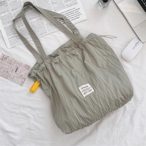 Close-up of sage green pleated tote bag with SOZAKKA label and yellow ribbon detail