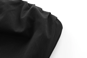 Detail of black strapless dress fabric showing pleated texture and smooth drape