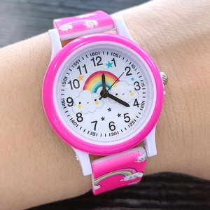 Close-up of pink and white kids watch with rainbow and cloud motifs on the wrist