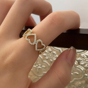 Detail of gold hollow heart ring with pave zircon stones worn on finger