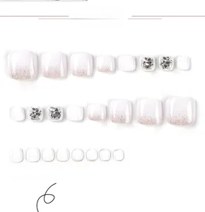 Détail de faux ongles de pieds dégradés blancs avec paillettes argentées et strass