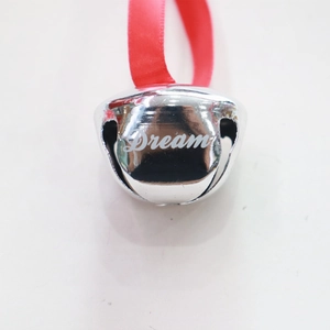 Close-up of 38mm silver metal bell with Dream engraving and red silk ribbon loop