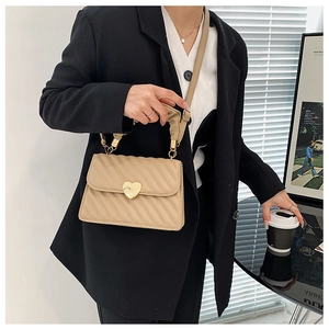 Detail of beige quilted crossbody bag with golden heart-shaped twist lock closure