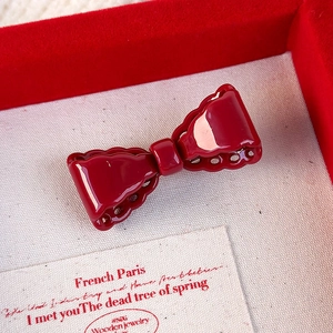 Detail of red bow-shaped hairpin with decorative scalloped edges in a jewelry gift box