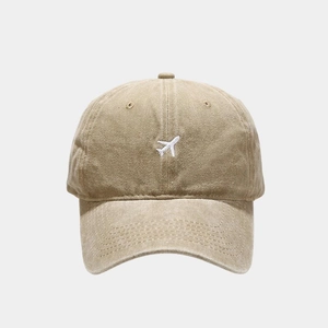 Detailed macro view of white airplane embroidery on a vintage khaki baseball cap