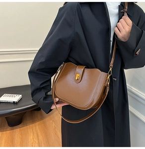 Detail of vintage brown saddle bag with gold metal buckle on a black trench coat