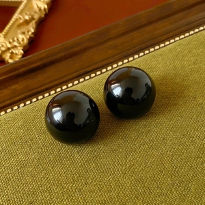 Macro shot of glossy black round beads on green fabric with vintage wooden accents