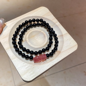 Detailed macro of double-layer beaded bracelet with a red engraved strawberry quartz stone