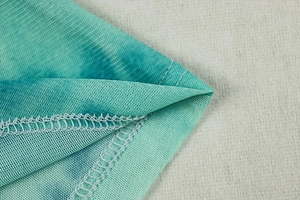 Close-up of mint green tie-dye mesh fabric with reinforced double stitching detail