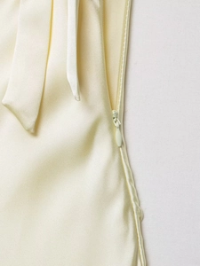 Close-up of a seamless invisible zipper on a beige satin midi dress showing fabric texture